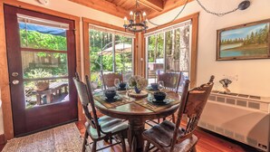 A wooden dining table with chairs, a chandelier, and a painting on the wall. - Guerneville~Hot Tub~Fenced Yard~Dog Friendly~Russian River~Cabin~Fern Woods (Guerneville)