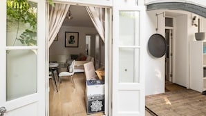 Een open verbinding naar een woonkamer met een bank, een eettafel en een stoel.