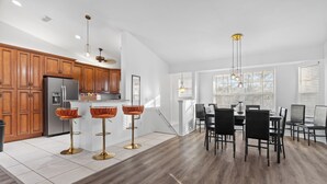 Eine moderne Küche mit Holzschränken, einem Edelstahlkühlschrank und einem Essbereich mit Tisch und Stühlen.