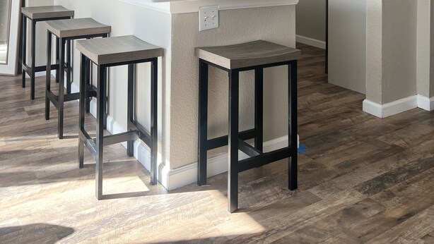 A modern kitchen with a central island, bar stools, a microwave, and pendant lighting.