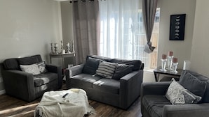 A modern living room with a grey sofa set, a coffee table, and a side table with candles.