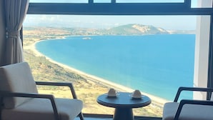 Habitación con vista a un paisaje costero, que incluye una mesa con dos tazas y dos sillas.