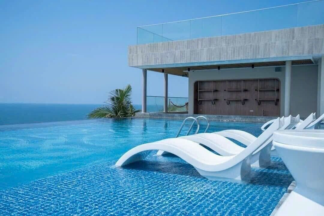 An infinity pool with white lounge chairs and a view of the ocean.