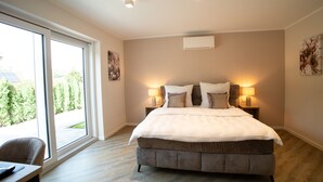 Een ruime slaapkamer met een groot bed, twee bedlampjes en uitzicht door middel van van top tot teen hoge ramen.