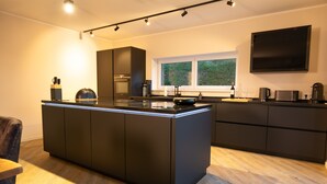 Een moderne keuken met een centraal eiland, inbouwapparatuur en een groot raam.