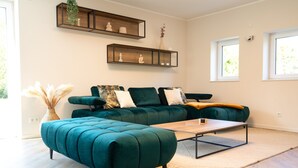 Een moderne woonkamer met een blauwgroene bank, een houten salontafel en een decoratieve plank erboven.