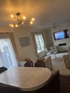 Relax in this stylish living room with a round dining table and comfortable seating, perfect for enjoying a meal or watching the scenic view on the flat-screen TV.