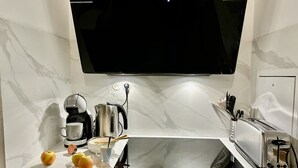 Una cocina moderna con televisor de pantalla plana sobre la encimera, estufa integrada y un tostador.