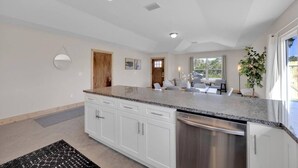 A modern kitchen with white cabinets, granite countertops, and stainless steel appliances. - 3 minute walk to the beach, outdoor shower, pet friendly, close to downtown (St. Augustine)