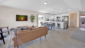A modern living room with a sofa, dining area, and kitchen. - 3 minute walk to the beach, outdoor shower, pet friendly, close to downtown (St. Augustine)
