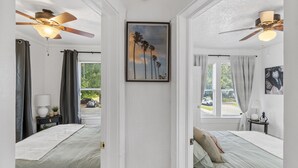Habitación de hotel con dos camas, ventiladores de techo, un cuadro y vistas al exterior.