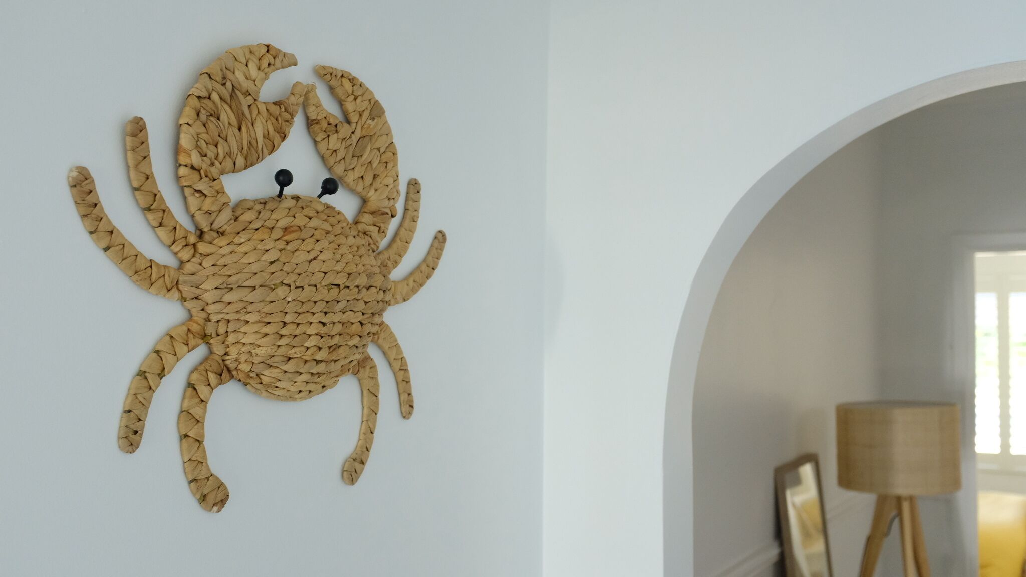 Une œuvre d’art murale tissée représentant un crabe sur un mur blanc.