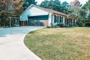 Une maison de plain-pied avec un garage, une véranda et une pelouse bien entretenue.