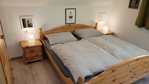 Una cama de madera con dos almohadas y una mesita de noche con una lámpara.