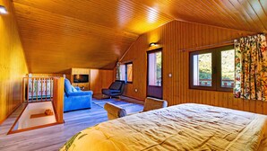 Un dormitorio de cabaña de madera acogedor, con una cama, un sofá azul y una silla.