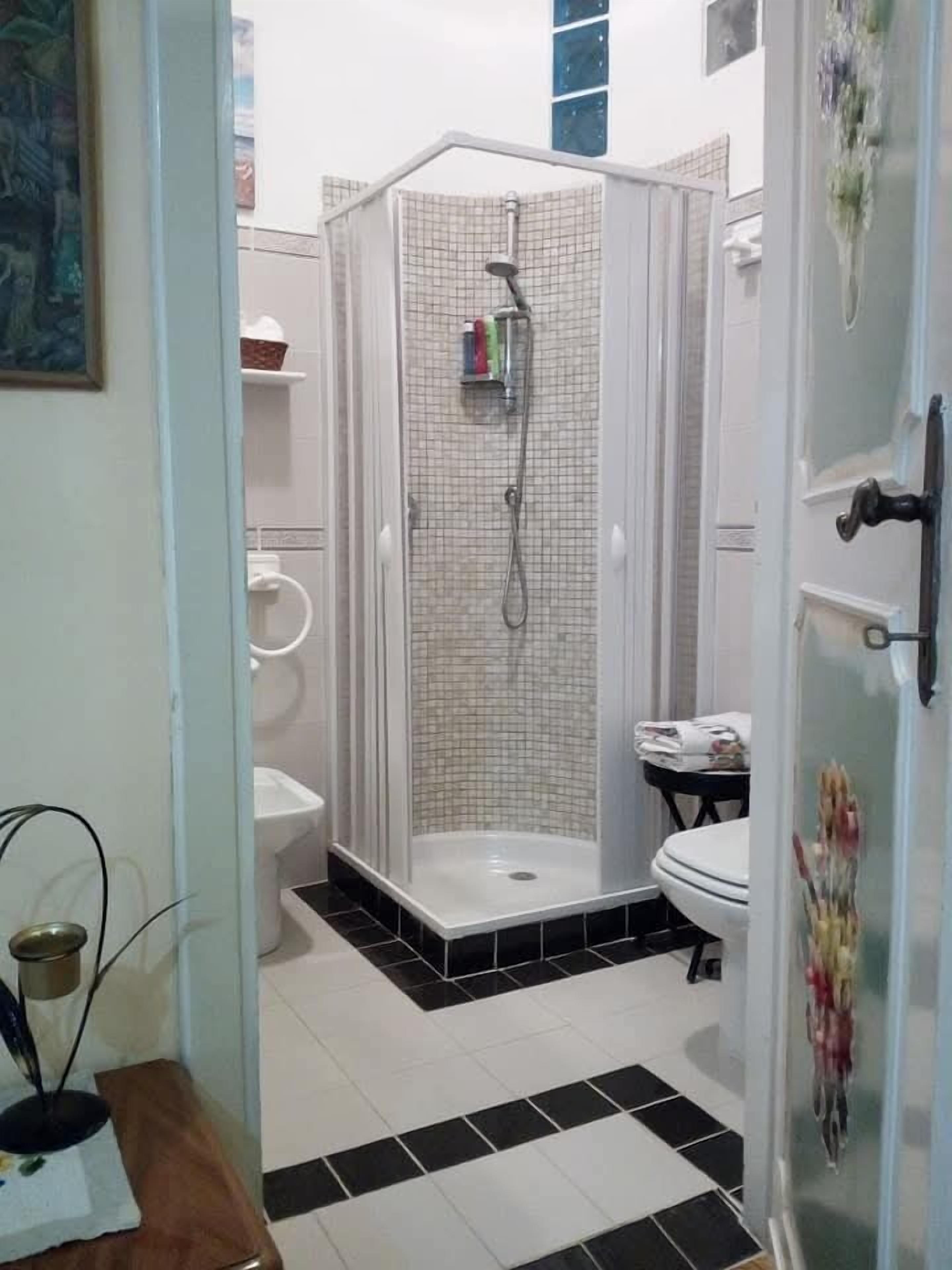 A bathroom with a shower enclosure, toilet, and sink.