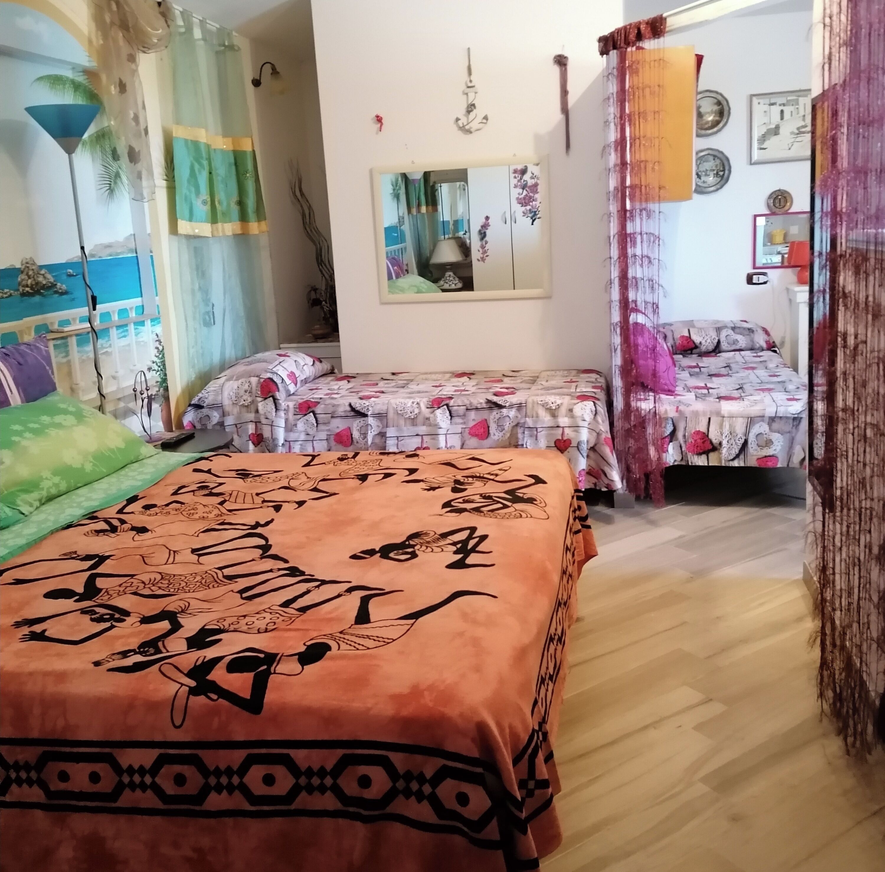 Une chambre avec deux lits, un grand miroir et une vue sur la mer par la fenêtre.