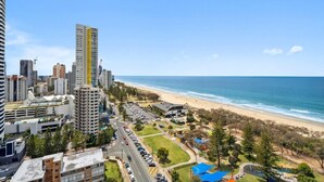 Un paisaje urbano costero con edificios altos, una playa y un estacionamiento.