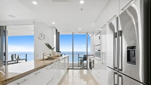 Una cocina moderna con vistas al mar, que cuenta con electrodomésticos de acero inoxidable y una isla grande.