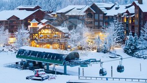 Un albergue cubierto de nieve con varias construcciones, un telesilla y una zona techada con asientos.