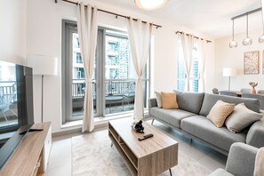 Ein modernes Wohnzimmer mit grauem Sofa, Couchtisch und Fernseher.