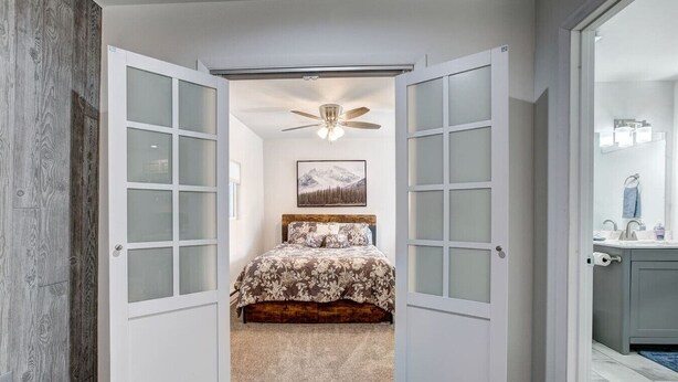 Ein Schlafzimmer mit einem Bett, einem Deckenventilator und einem Bild an der Wand.