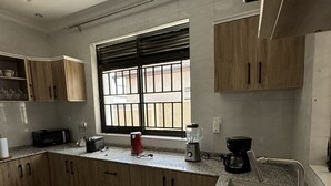 Een keuken met houten kastjes, een granieten aanrechtblad, een roestvrijstalen spoelbak en een raam met tralies.