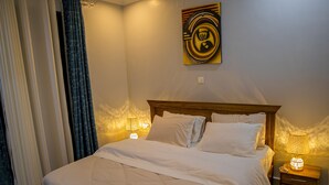 Een opgemaakt bed met witte lakens, een houten hoofdbord en twee bedlampen.