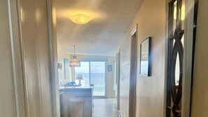 A hallway with wooden flooring, a kitchen area with a window, and a view of the ocean. - Oceanfront Wells Beach Condo - Ocean Surf #6 (Wells)