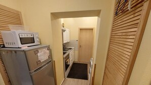 A narrow kitchen with a microwave, refrigerator, and oven.