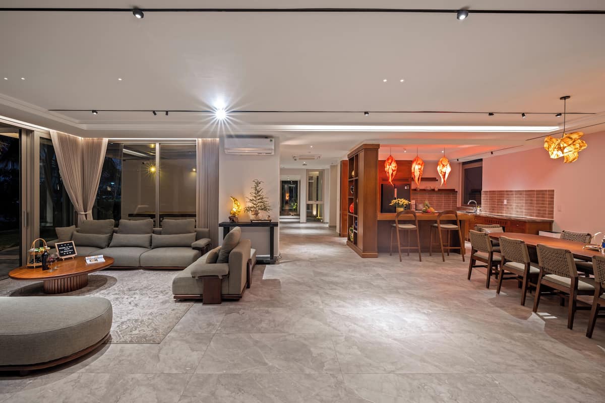 A modern living room with a sofa, coffee table, and dining area with chairs and a table.