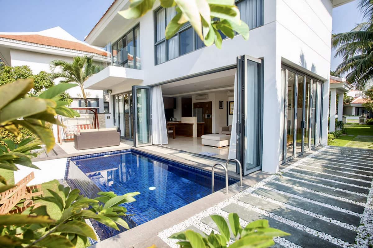 A modern two-story house with a swimming pool, large glass doors, and a well-maintained garden.