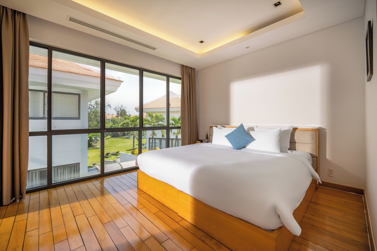 A spacious bedroom with a large bed, a view of the outdoors, and a modern design.
