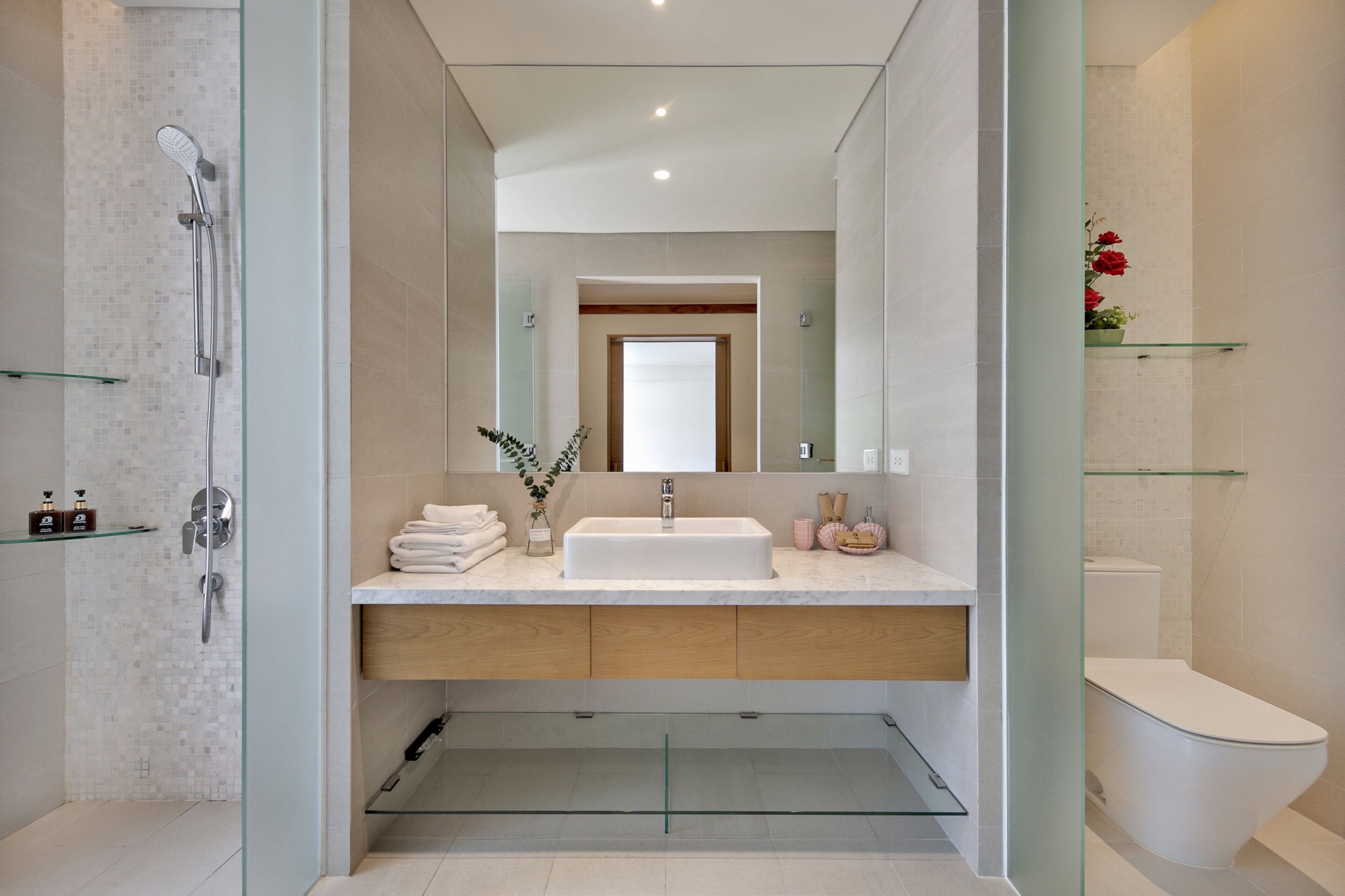 A modern bathroom with a glass-enclosed shower, a white sink, and a toilet.