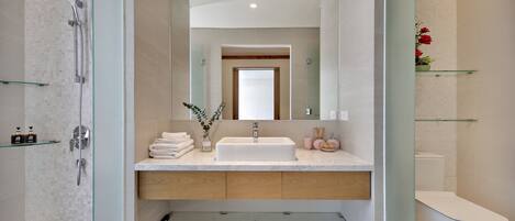 A modern bathroom with a glass-enclosed shower, a white sink, and a toilet.