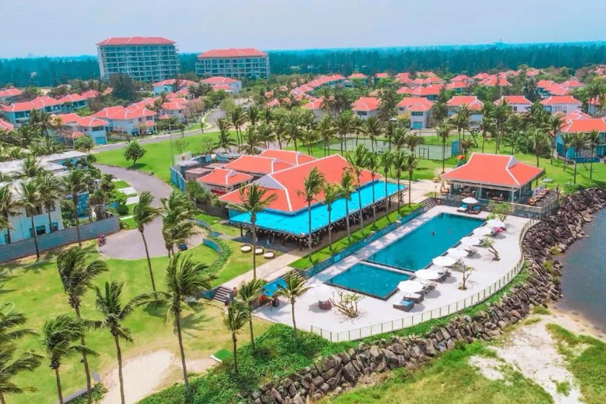 A resort with multiple buildings, a central pool, and a surrounding water body.