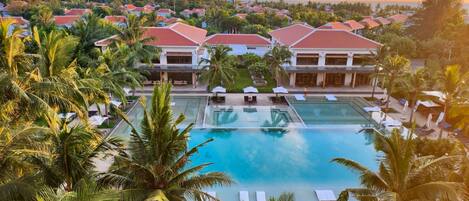 A resort with multiple swimming pools, palm trees, and buildings with red roofs.