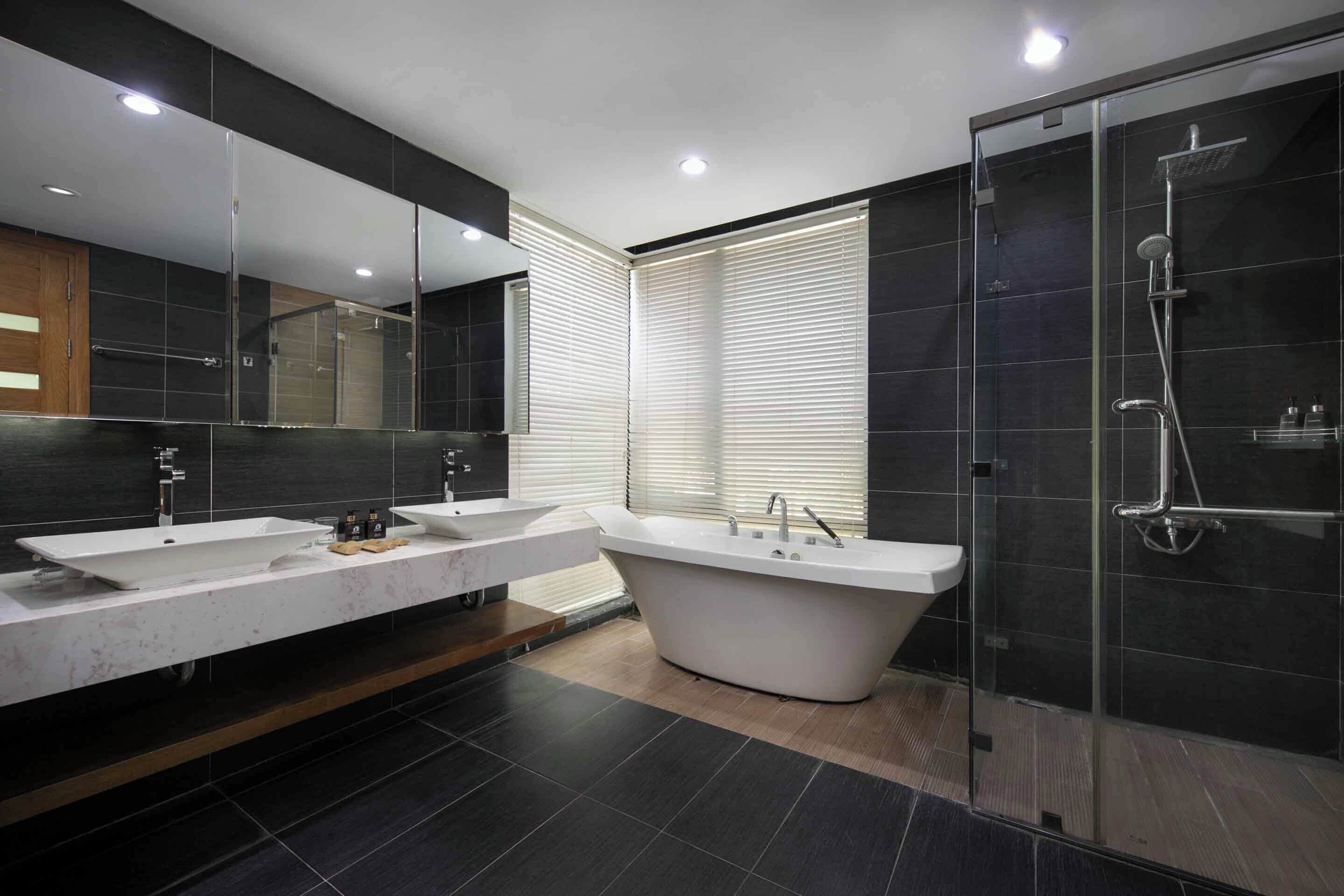 Une salle de bain moderne avec deux vasques, une baignoire sur pieds et une douche séparée par des parois en verre.
