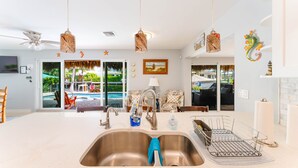 Una cucina moderna con una grande isola, elettrodomestici in acciaio inossidabile e vista su una zona piscina all'aperto.