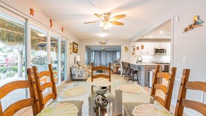 Un'ampia sala da pranzo con tavolo in vetro, sedie in legno e una ventola a soffitto.