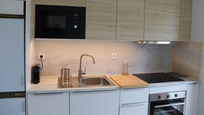 A modern kitchen with a built-in microwave, stainless steel sink, and an oven. - Árvore Cozy com Jardim (Árvore)