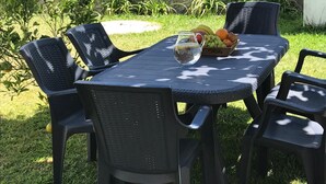 An outdoor table with chairs, a pitcher of water, and a fruit basket. - Árvore Cozy com Jardim (Árvore)