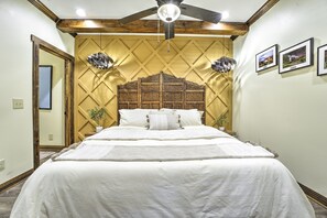 Ein Schlafzimmer mit einem großen Bett, einem Holz-Kopfteil und einem Deckenventilator.