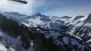 A ski lift chair suspended above a snowy mountain landscape with clear skies.