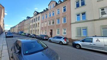 A street lined with parked cars and multi-story residential buildings.