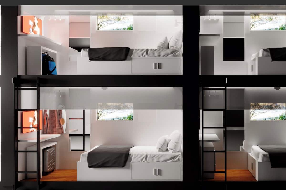 A modern, multi-level hotel room with a split-level design, including a bedroom and a living area with a view of the outdoors.