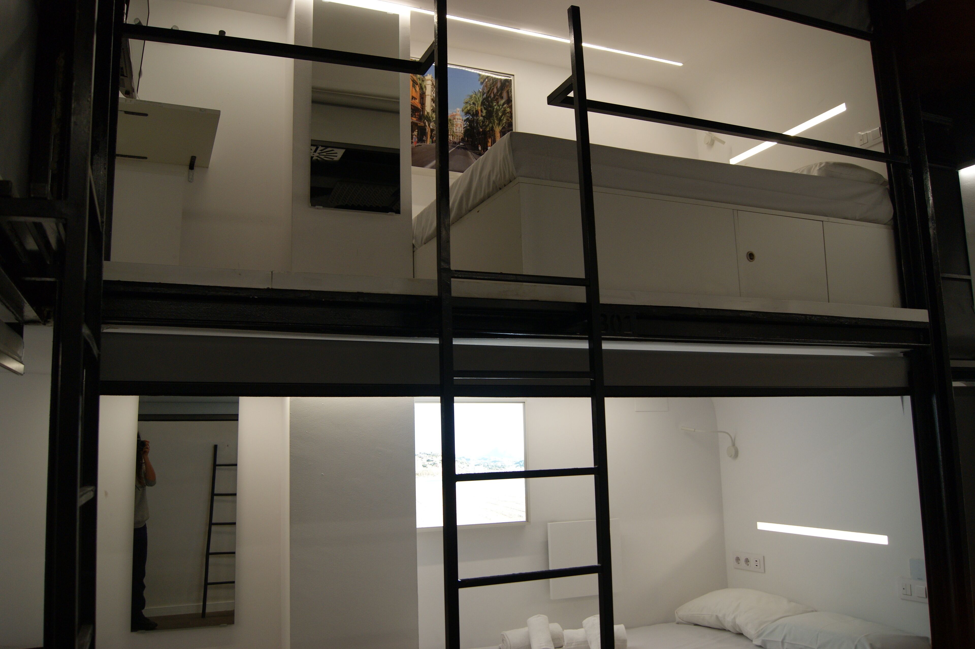 Una camera con un letto a castello, una scala, una finestra e un quadro appeso al muro.