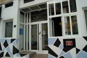 A building with a white facade, a glass door entrance, and a sign indicating 'PODS MALAGA'. - MPods Málaga (Málaga)