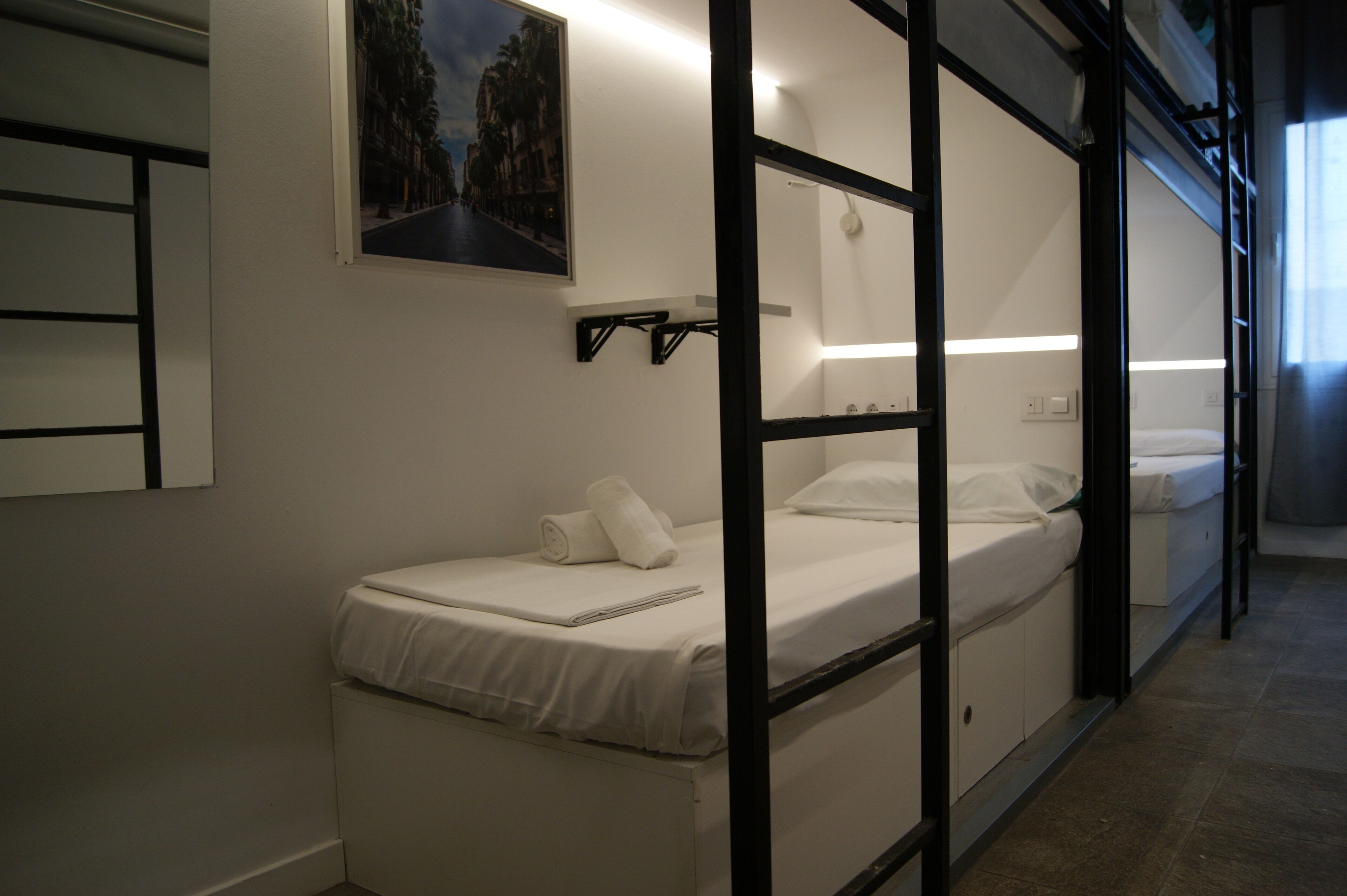 Una habitación de hotel con literas, un cuadro en la pared y una mesita de noche.
