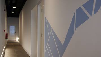 A hallway with a geometric wall design, a fire extinguisher, and a door at the end.
